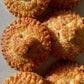 Golden brown, round pies with Mickey Mouse head pie crust decor, sprinkled with raw sugar and sitting on a white counter top.